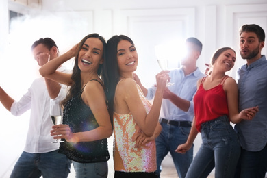 Photo of Couple of happy friends with champagne dancing at party