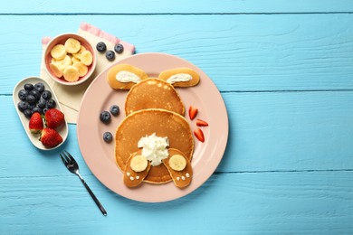 Creative serving for kids. Plate with cute bunny made of pancakes, berries, cream and banana on light blue wooden table, flat lay. Space for text