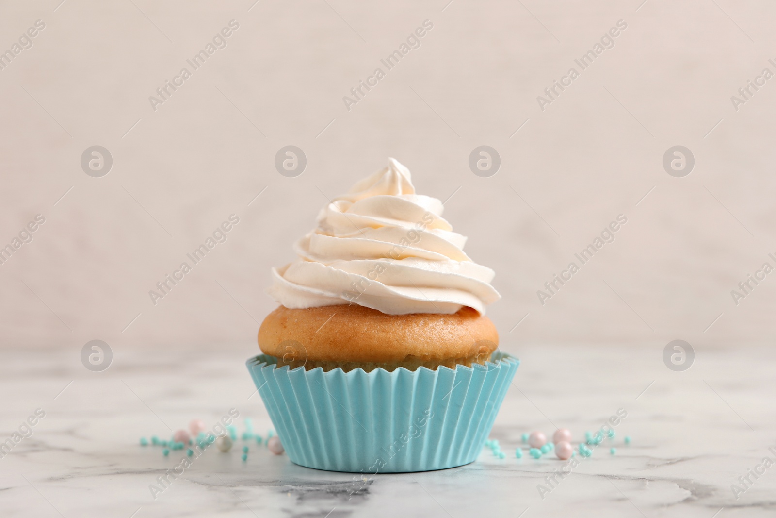 Photo of Delicious cupcake decorated with cream on white marble table