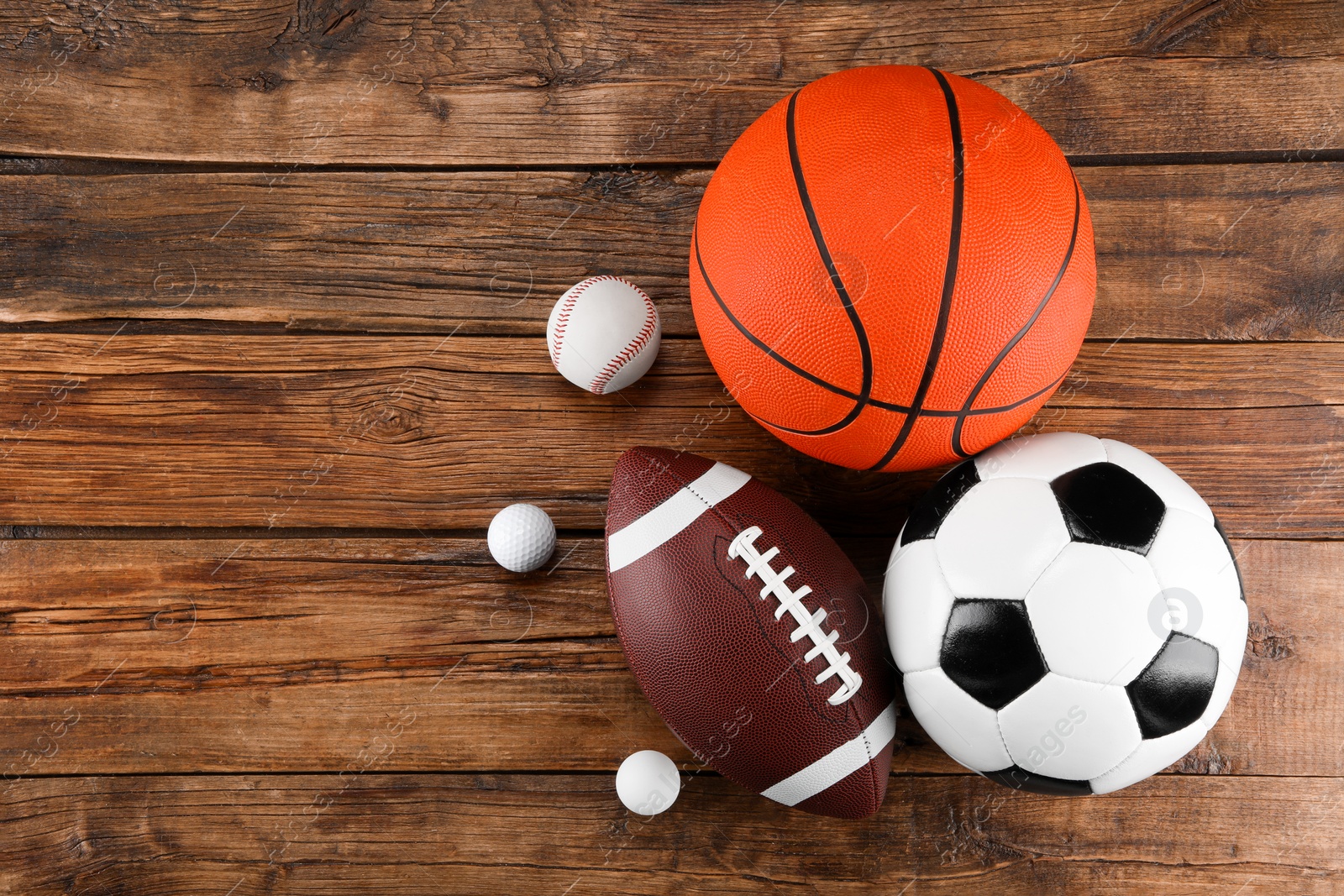 Photo of Many different sports balls on wooden background, flat lay. Space for text