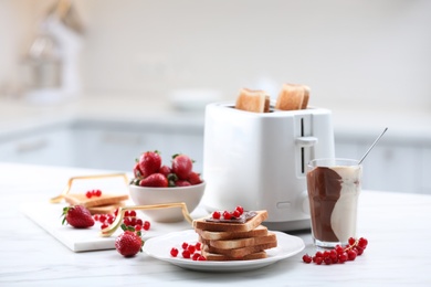 Tasty breakfast with toasted bread and fresh berries on white marble table in kitchen