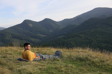 Man in sleeping bag enjoying mountain landscape, space for text