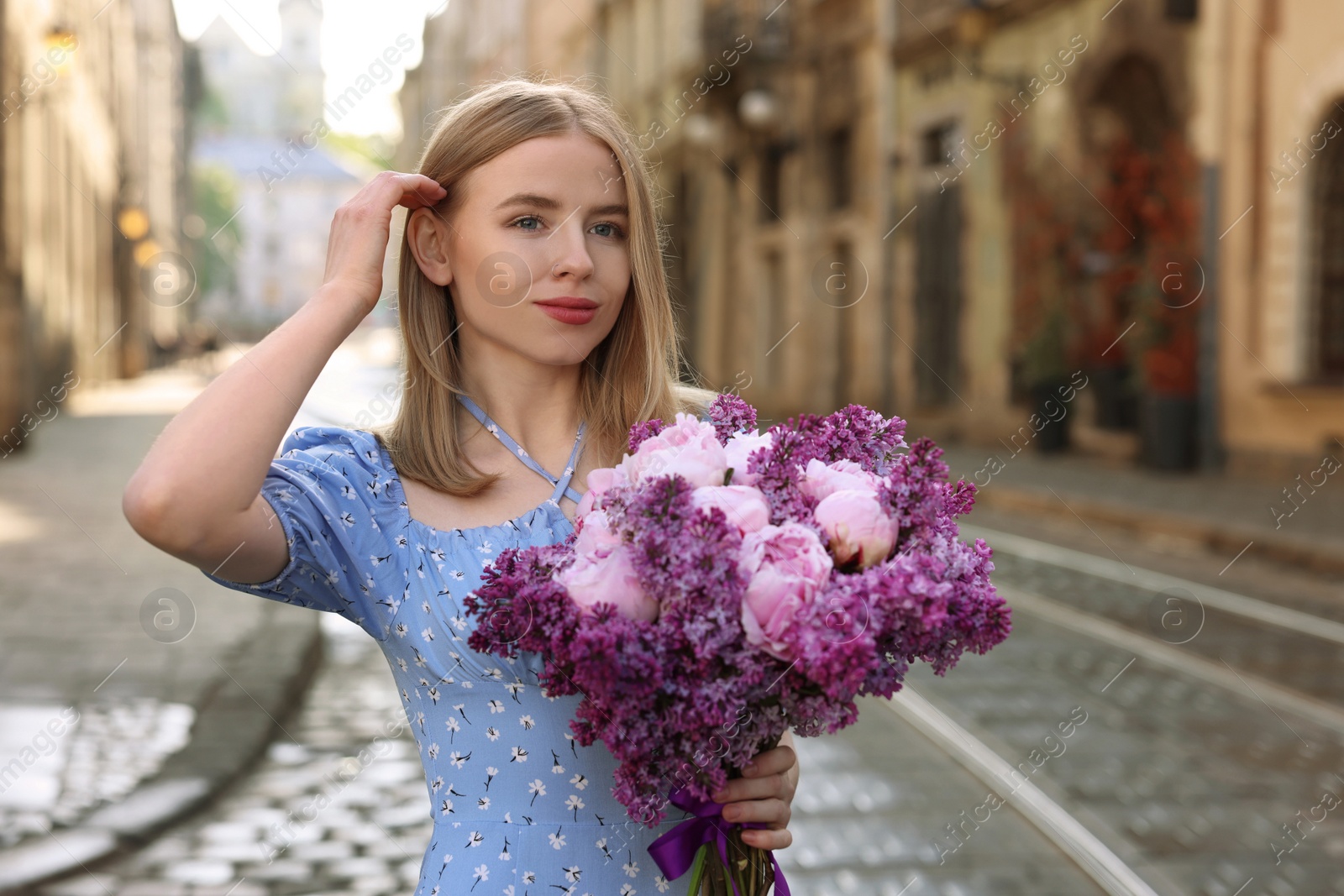 Photo of Beautiful woman with bouquet of spring flowers on city street