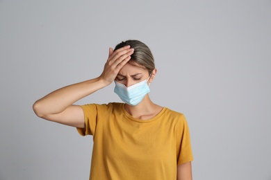 Photo of Stressed woman in protective mask on grey background. Mental health problems during COVID-19 pandemic