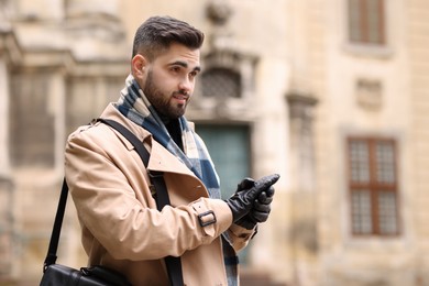 Photo of Handsome man in warm scarf on city street. Space for text