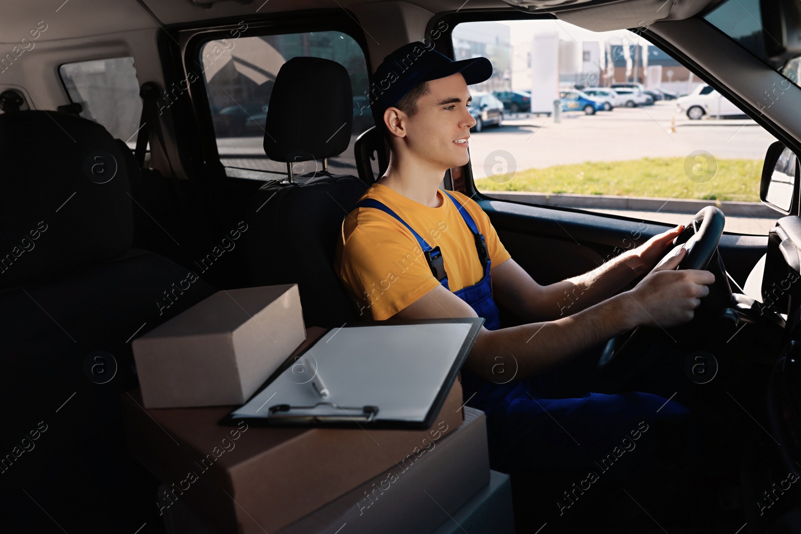 Photo of Courier with clipboard and parcels in car. Delivery service