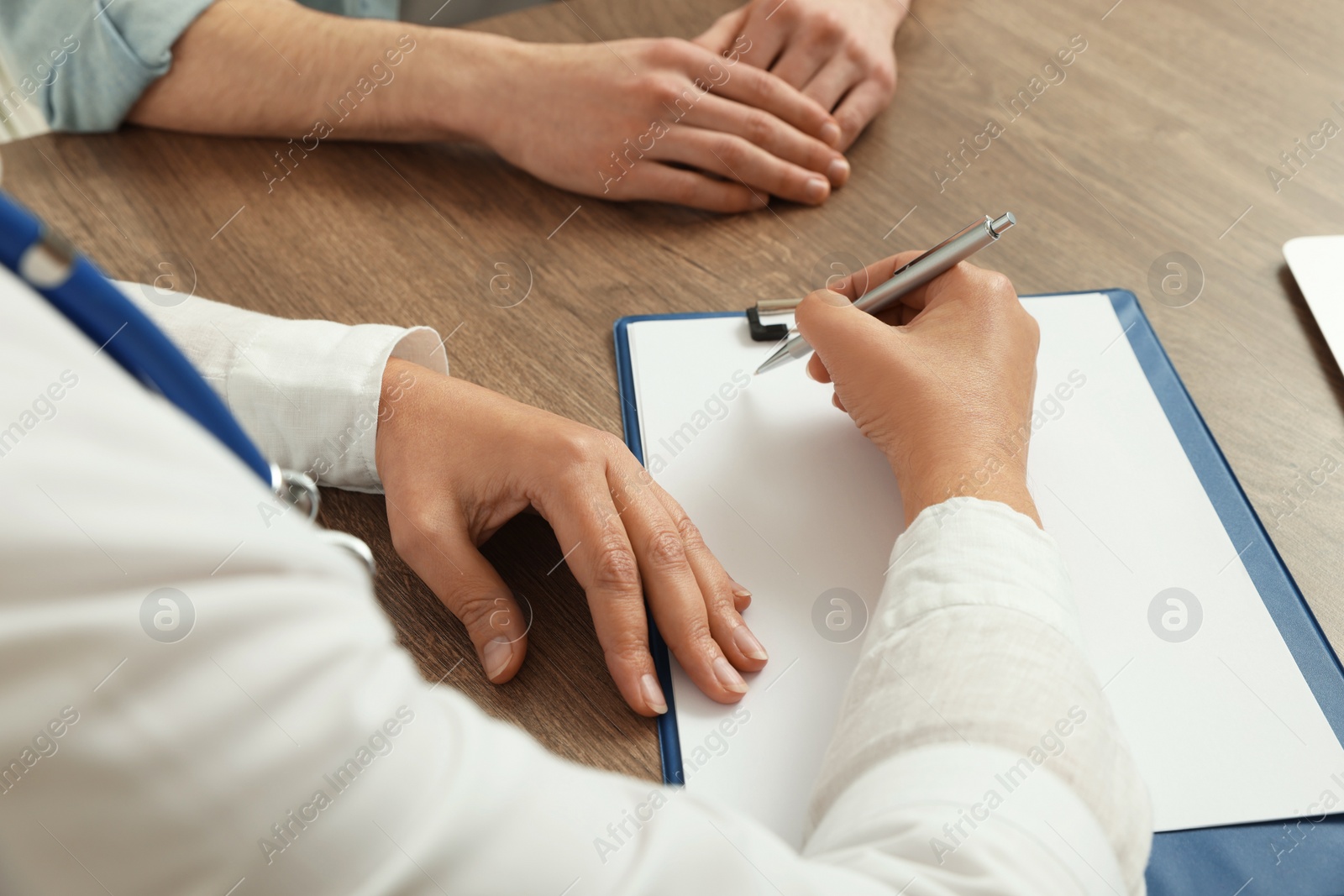 Photo of Professional doctor working with patient at wooden table, closeup