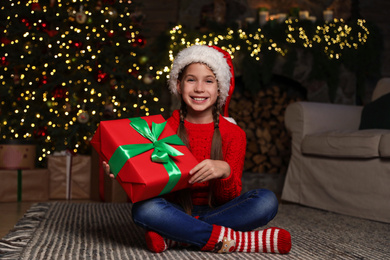 Photo of Happy child with Christmas gift on floor at home