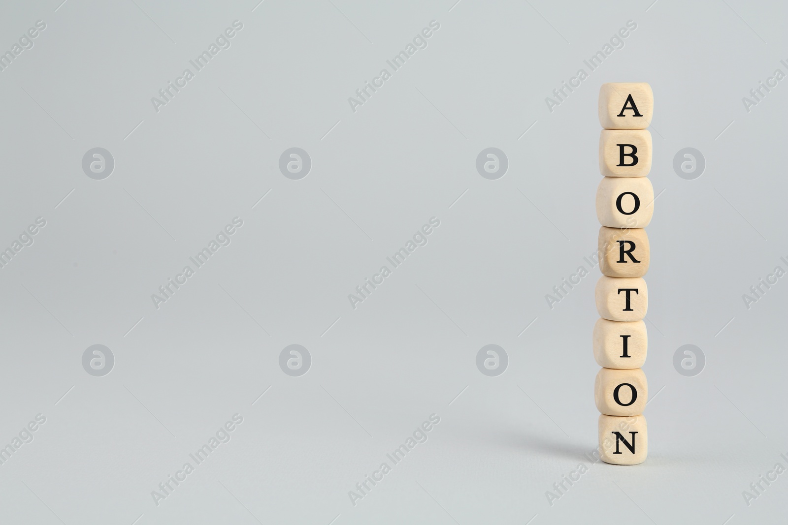 Photo of Word Abortion made of wooden cubes on light grey background. Space for text