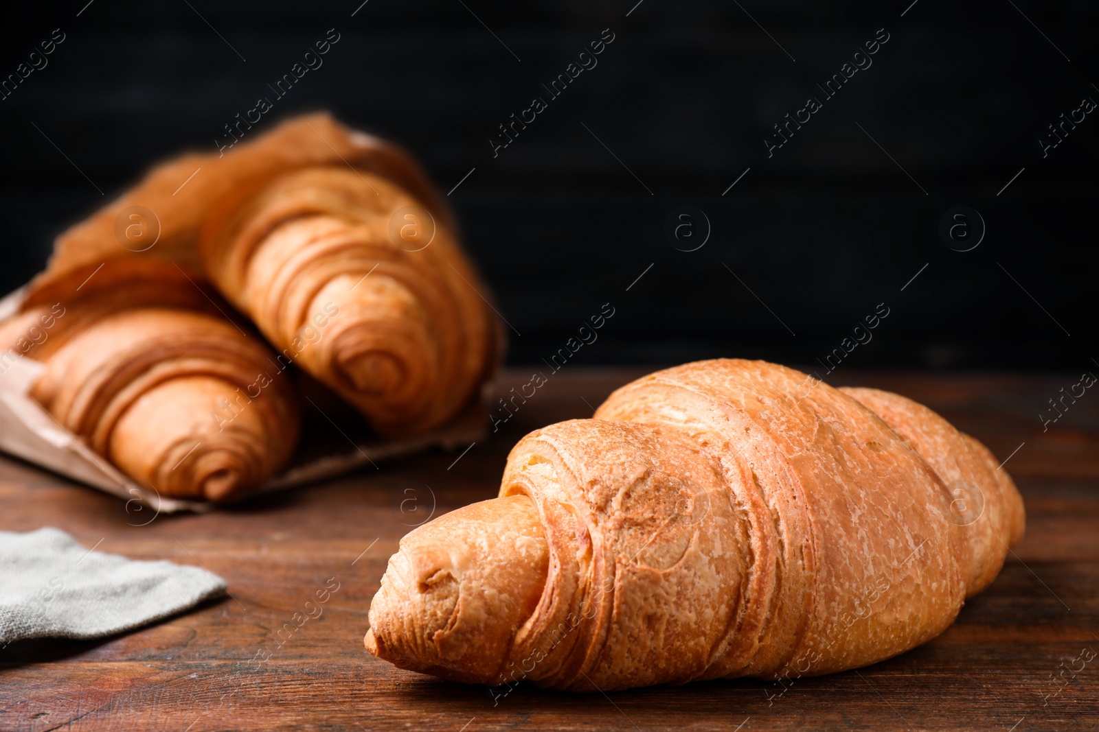 Photo of Tasty fresh croissant on wooden table, closeup