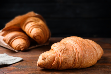 Tasty fresh croissant on wooden table, closeup