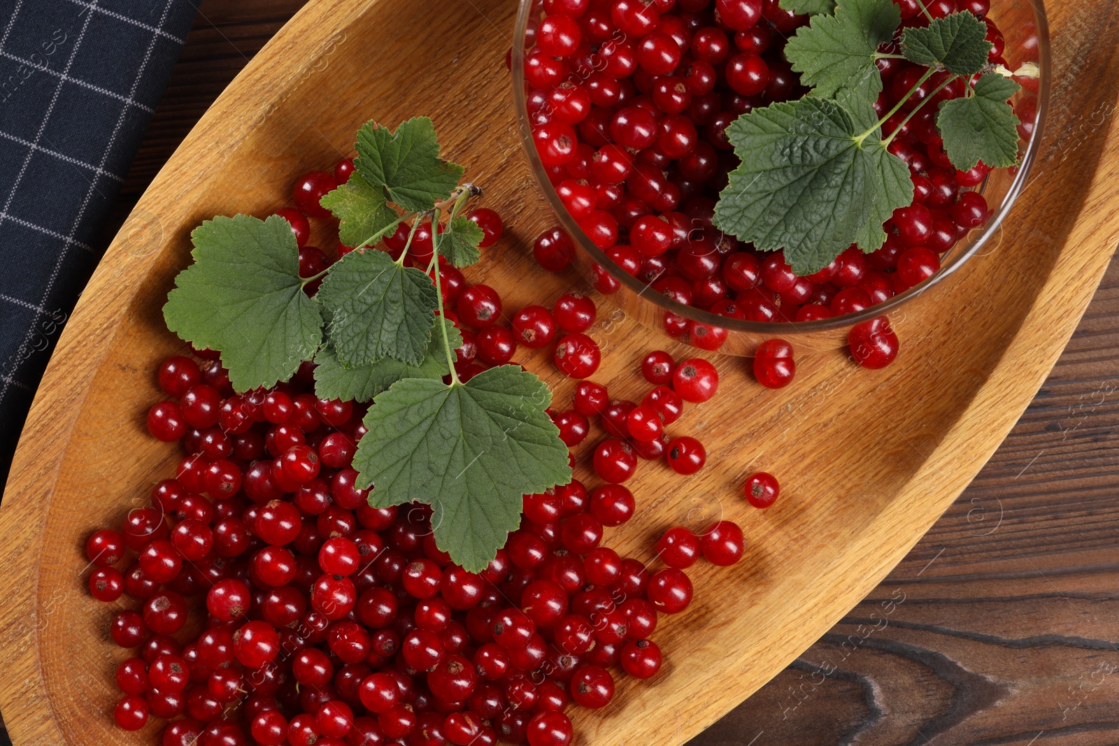 Photo of Ripe red currants and leaves on wooden table, top view