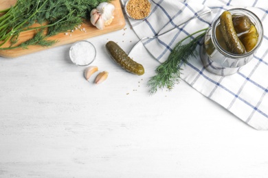 Flat lay composition with jar of pickled cucumbers on white wooden table, space for text