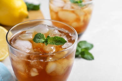 Photo of Delicious iced tea in glass on light table, closeup. Space for text