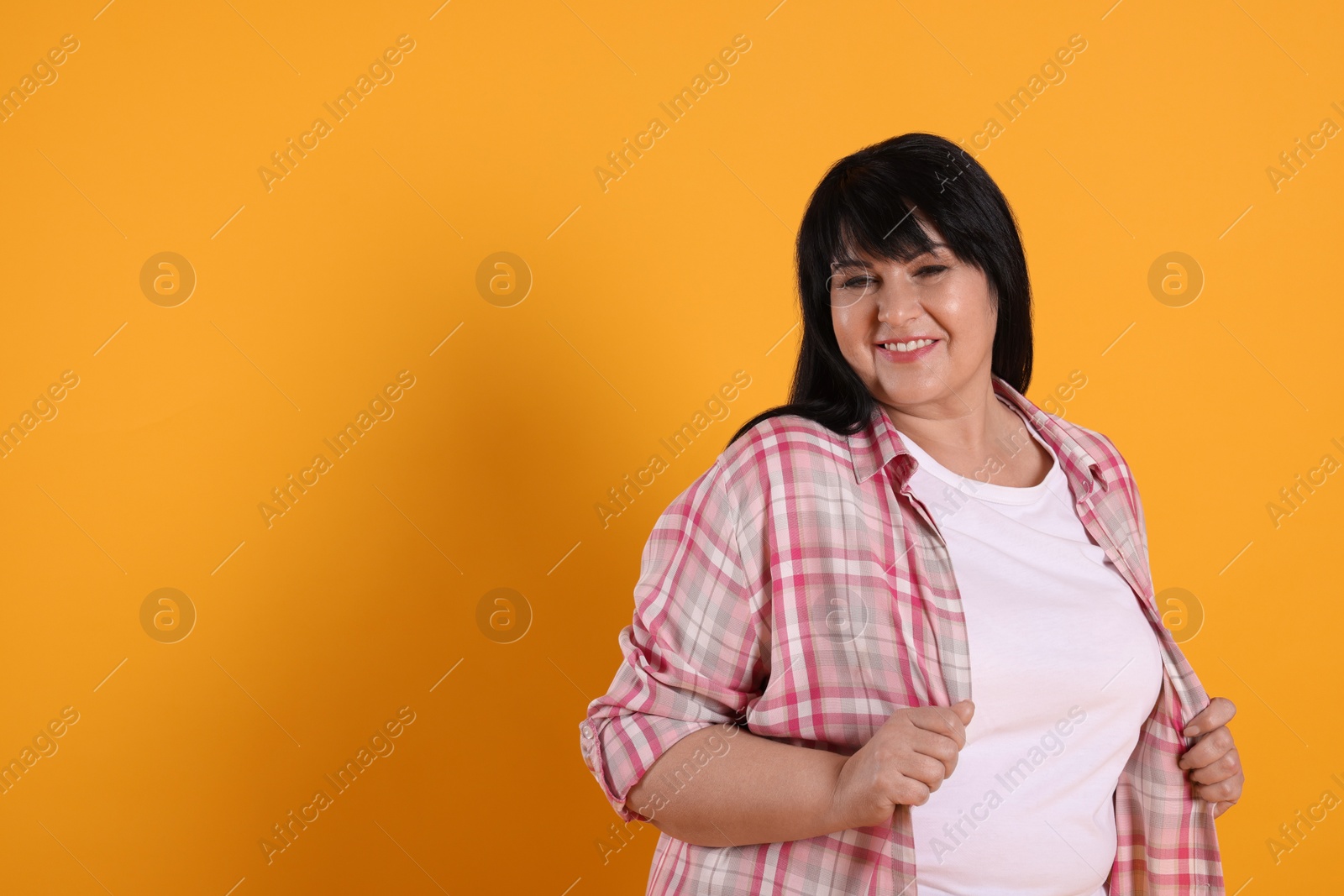 Photo of Beautiful overweight mature woman with charming smile on yellow background. Space for text