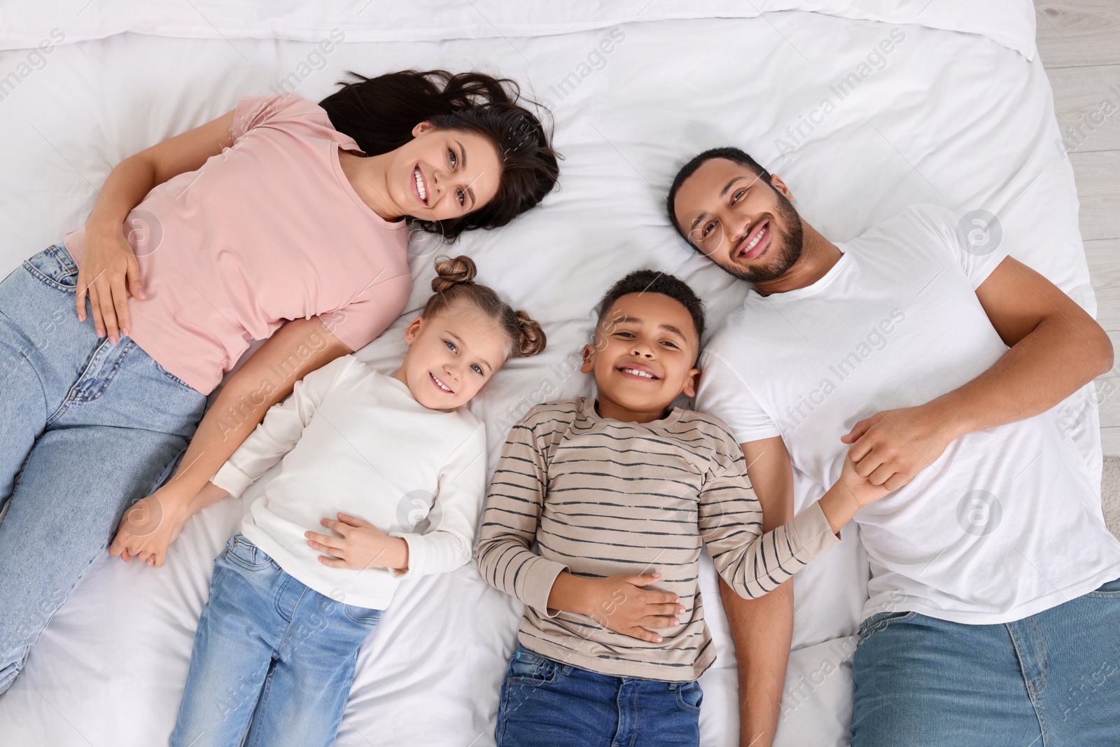 Photo of Happy international family lying on bed, top view