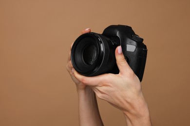 Photographer with camera on brown background, closeup. Space for text