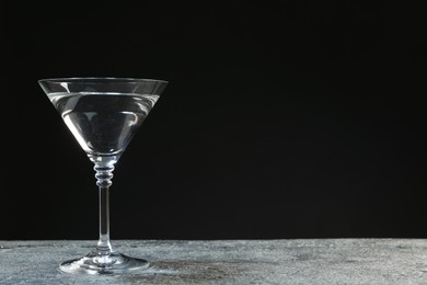 Martini cocktail on grey table against dark background. Space for text