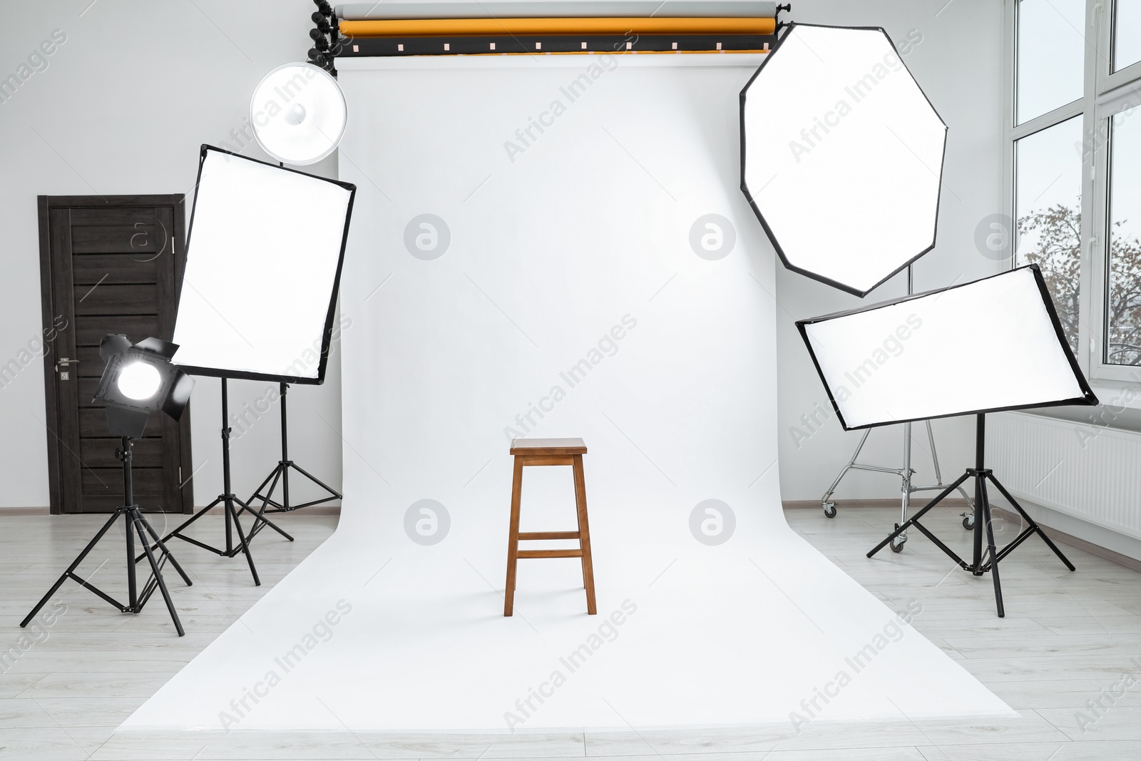 Photo of Interior of modern photo studio with bar stool and professional lighting equipment