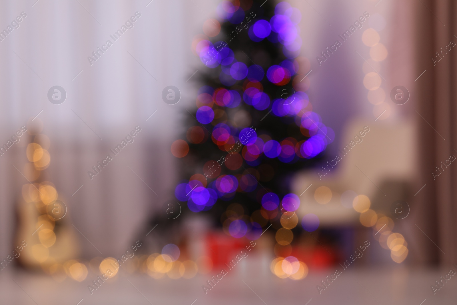 Photo of Blurred view of fir tree, Christmas gifts, guitar and armchair in living room