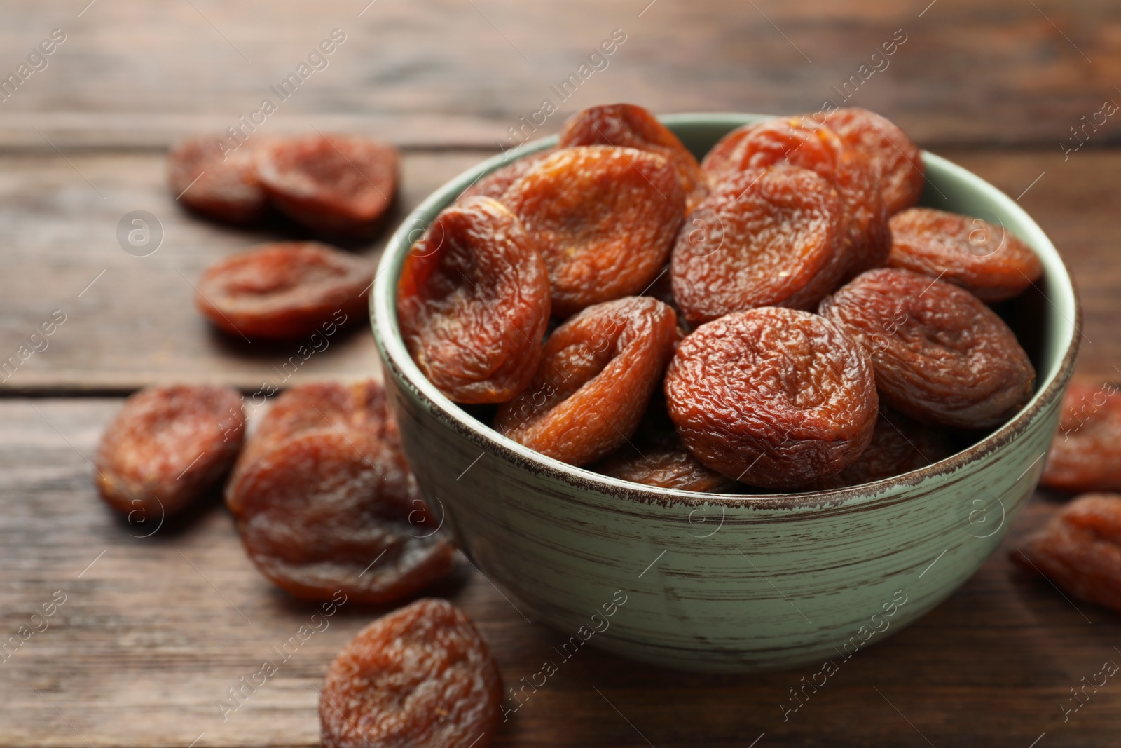 Photo of Bowl of tasty apricots on wooden table, closeup. Dried fruits