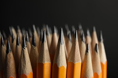 Photo of Many graphite pencils on black background, closeup