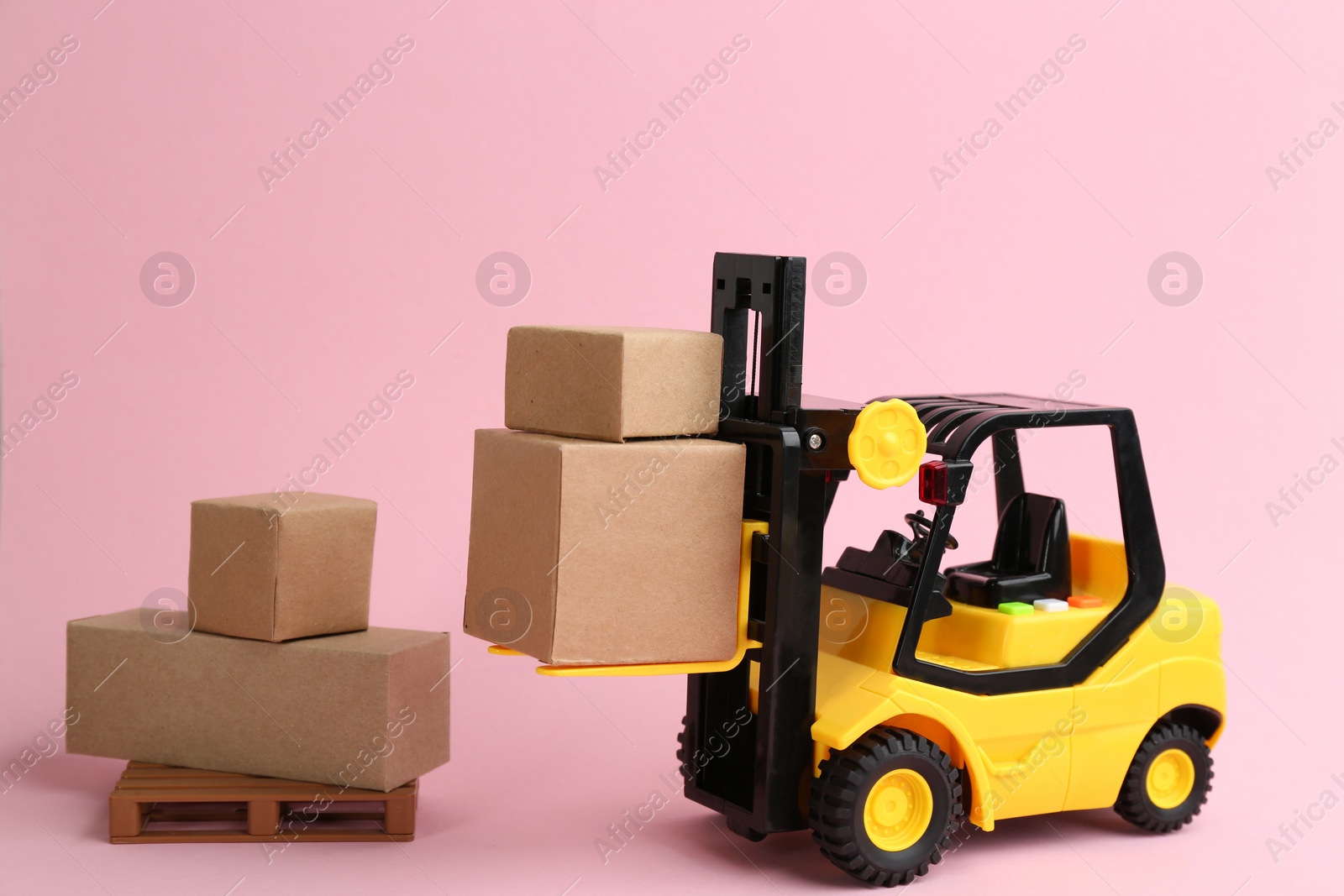 Photo of Forklift model and carton boxes on light pink background. Courier service