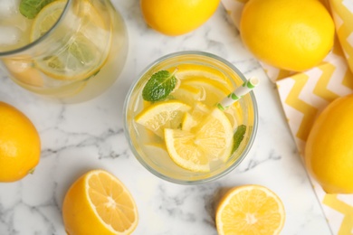 Photo of Cool freshly made lemonade and fruits on white marble table, flat lay