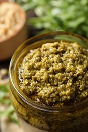 Jar of tasty arugula pesto on table, closeup