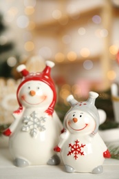 Decorative snowmen on white wooden table, space for text