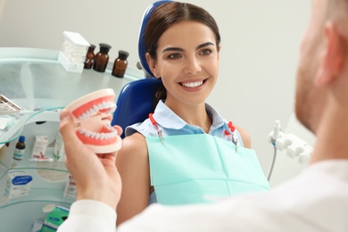 Photo of Professional dentist showing patient jaws model in clinic