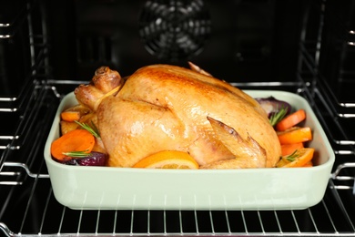 Baking pan with chicken, oranges and vegetables in oven