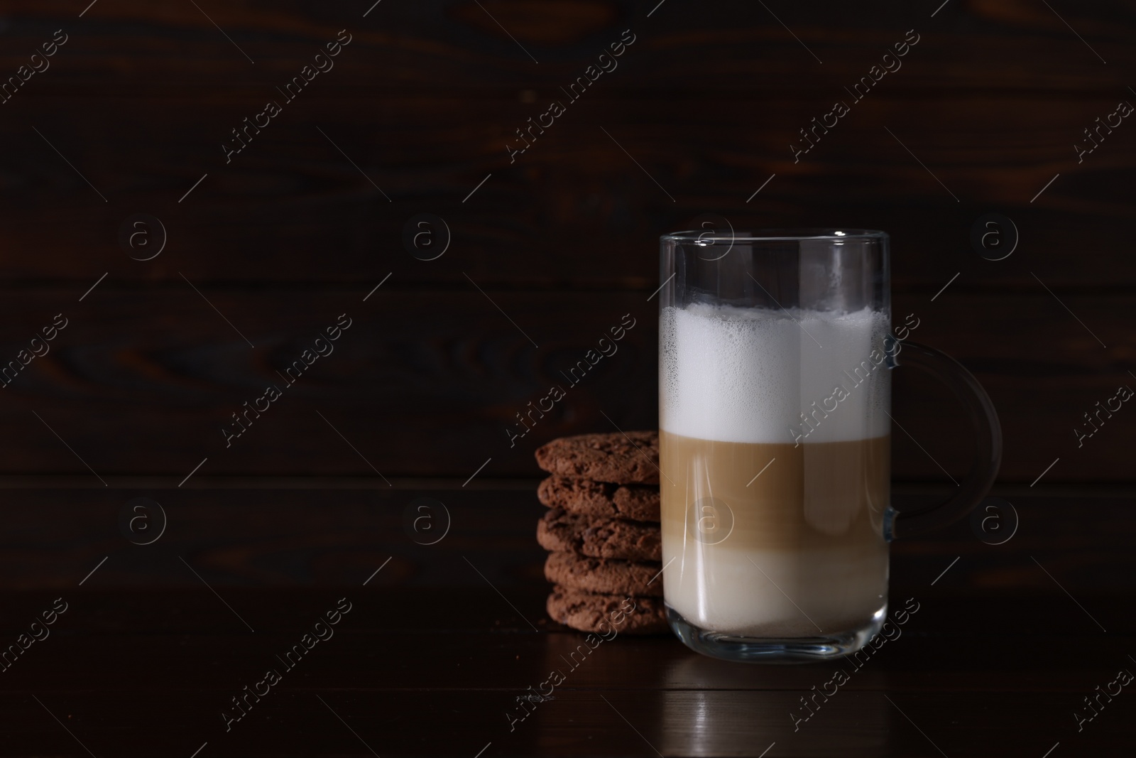 Photo of Cup of aromatic latte macchiato and chocolate cookies on wooden table. Space for text