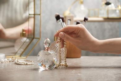 Photo of Woman taking crystal bottle of luxurious perfume from dressing table, closeup. Space for text