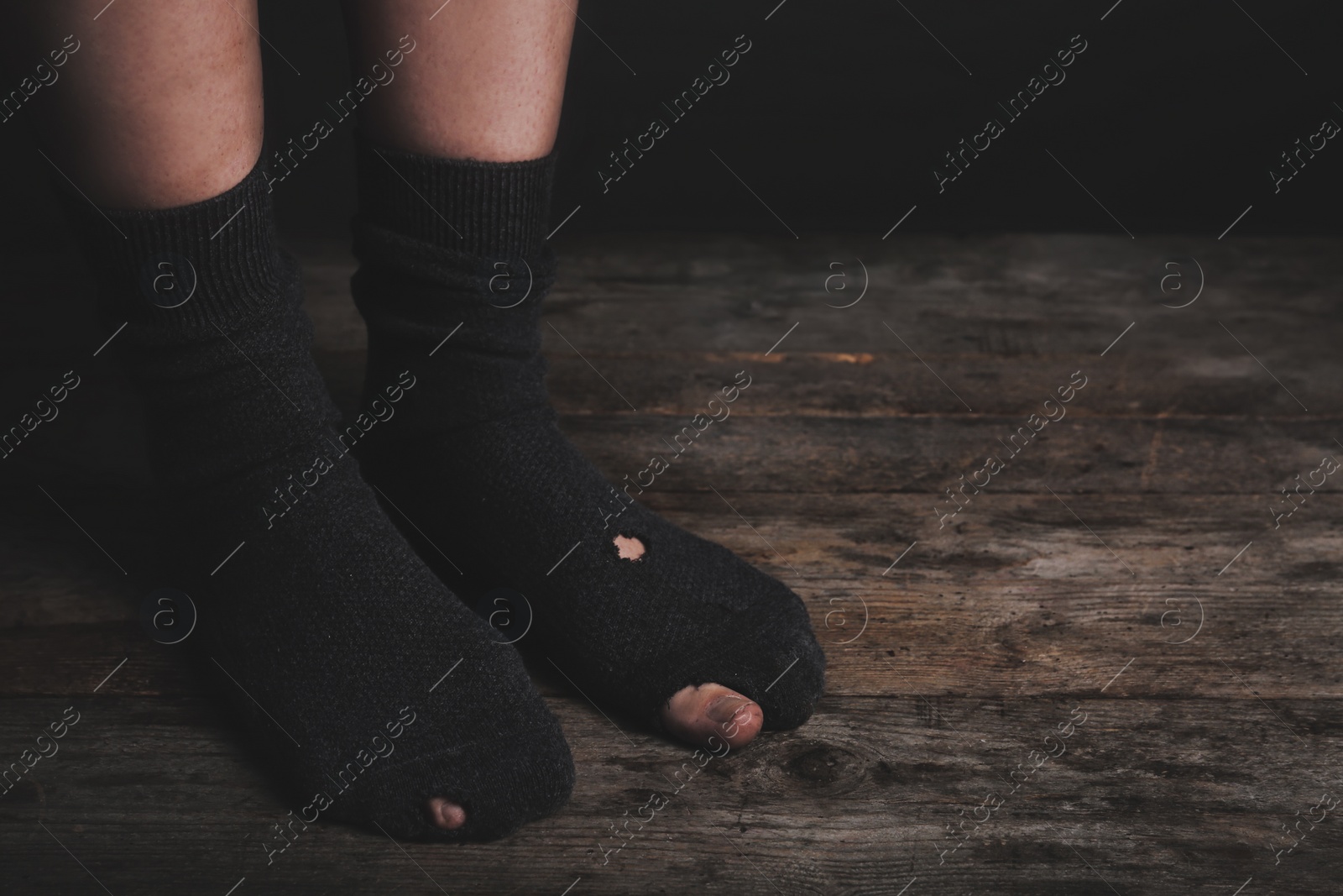 Image of Poor person in shabby socks on wooden floor, closeup