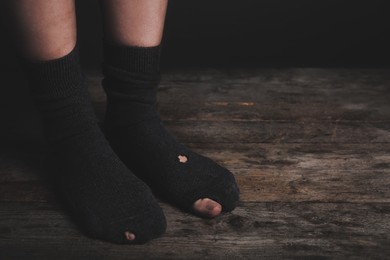 Image of Poor person in shabby socks on wooden floor, closeup