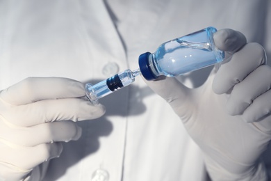 Doctor filling syringe with vaccine from vial, closeup