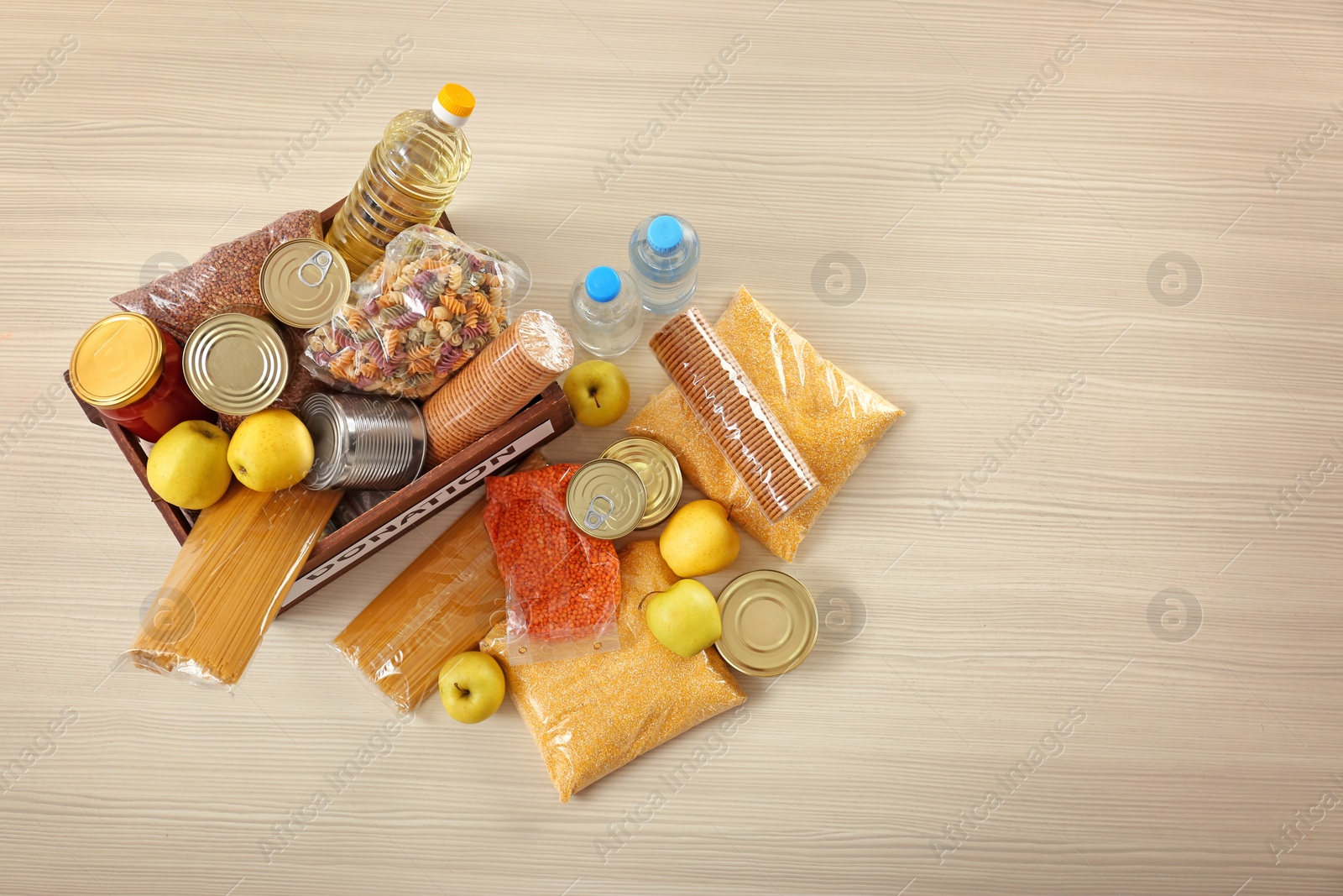 Photo of Donation box and different products on wooden table, top view. Space for text