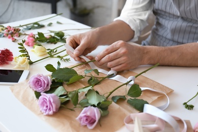 Male florist creating beautiful bouquet at table, closeup