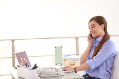 Young woman talking on phone at workplace