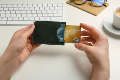 Woman holding leather card holder with credit cards at white table, closeup