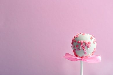 Photo of Tasty cake pop with bow on lilac background