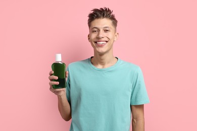 Photo of Young man with mouthwash on pink background