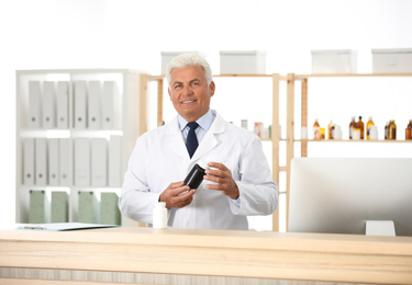 Photo of Professional pharmacist with bottle of medicine in drugstore