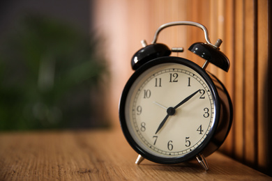 Alarm clock on wooden table at home. Morning time