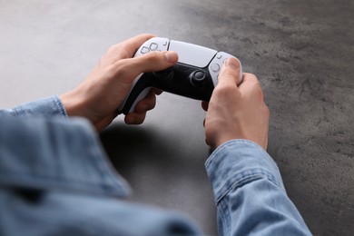 Photo of Man using wireless game controller at grey table, closeup