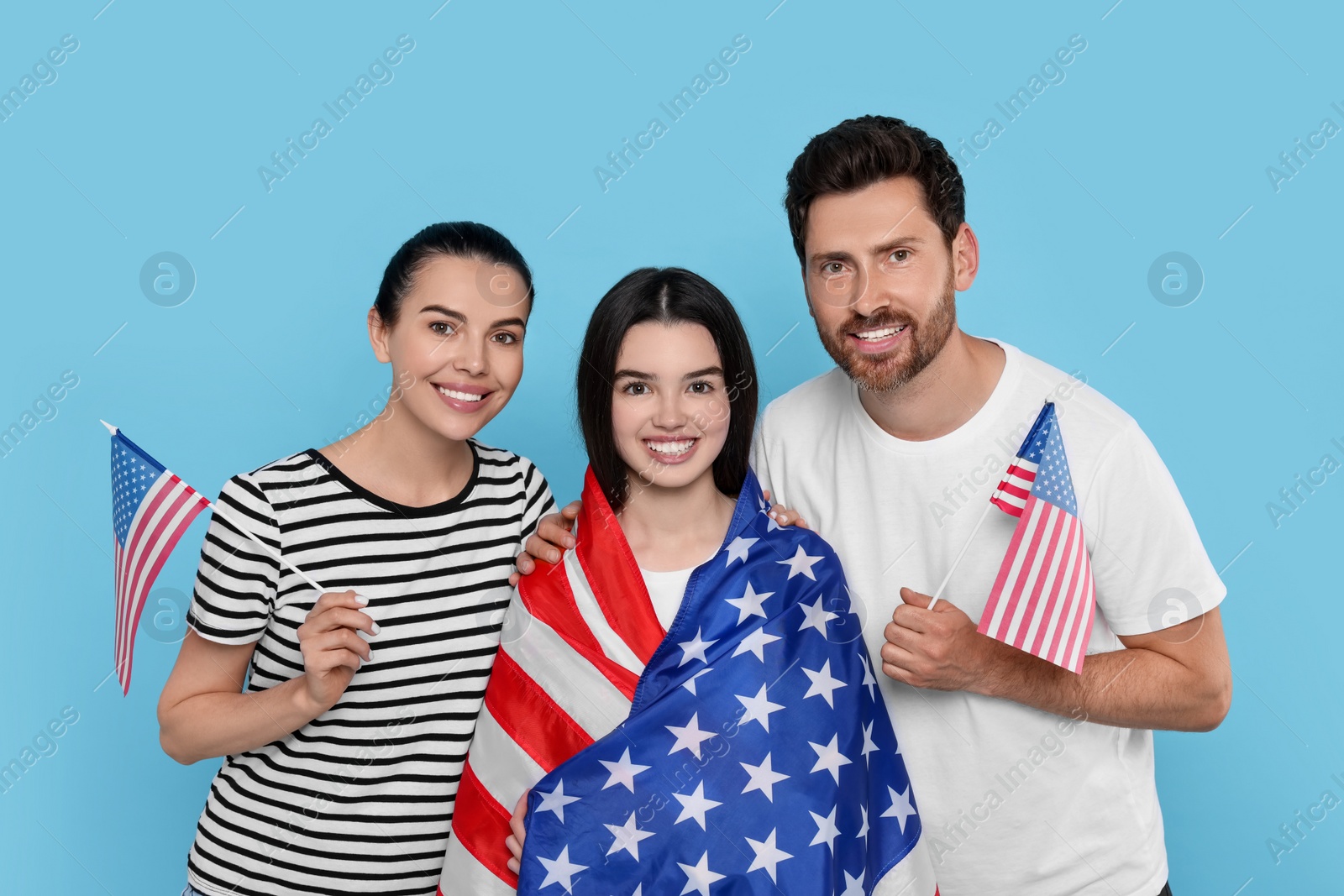 Photo of 4th of July - Independence Day of USA. Happy family with American flags on light blue background