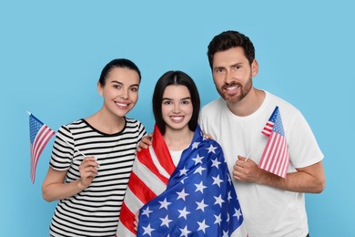 4th of July - Independence Day of USA. Happy family with American flags on light blue background