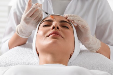 Doctor giving facial injection to young woman in clinic. Cosmetic surgery