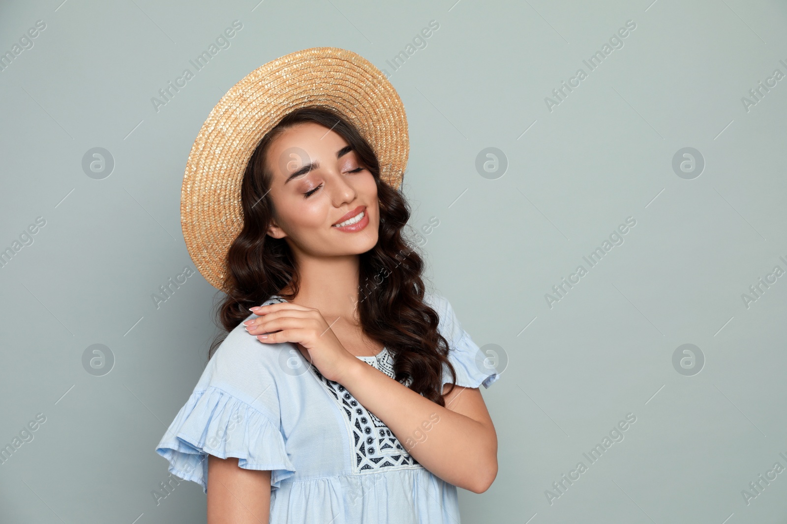 Photo of Beautiful young woman with straw hat on light grey background. Space for text